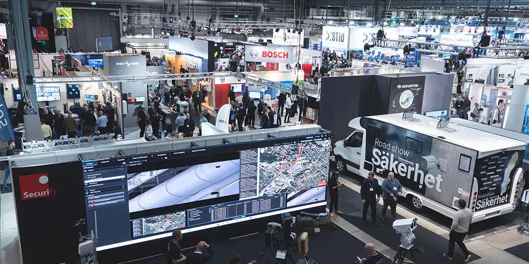 Vy över en stor mässhall på SKYDD med utställarstånd, tekniklösningar och många besökare i rörelse.