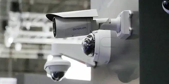 Flera avancerade övervakningskameror, inklusive en Avigilon-kamera, monterade på en vägg på säkerhetsmässan SKYDD.