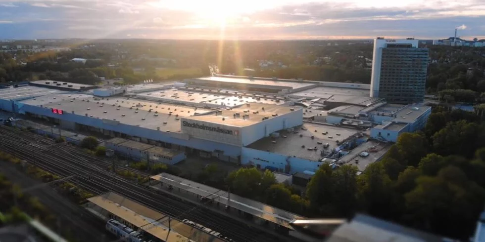 Aerial view of Stockholmsmässan in Älvsjö at sunset, with the exhibition halls, hotel and railway tracks in the foreground.