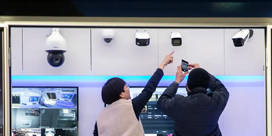 Besökare tittar på olika övervakningskameror i en monter och dokumenterar med mobiltelefon.