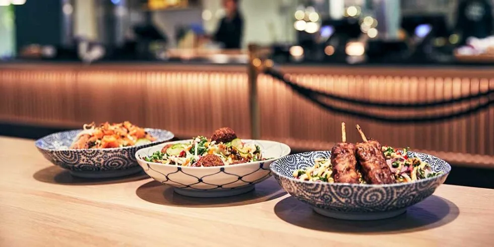 Tre tallrikar med olika maträtter, står på med blått mönster står på ett bord. I