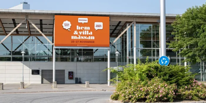 Large façade-mounted banner at the entrance of Stockholmsmässan promoting the Hem & Villa exhibition, visible from the roundabout outside the venue.