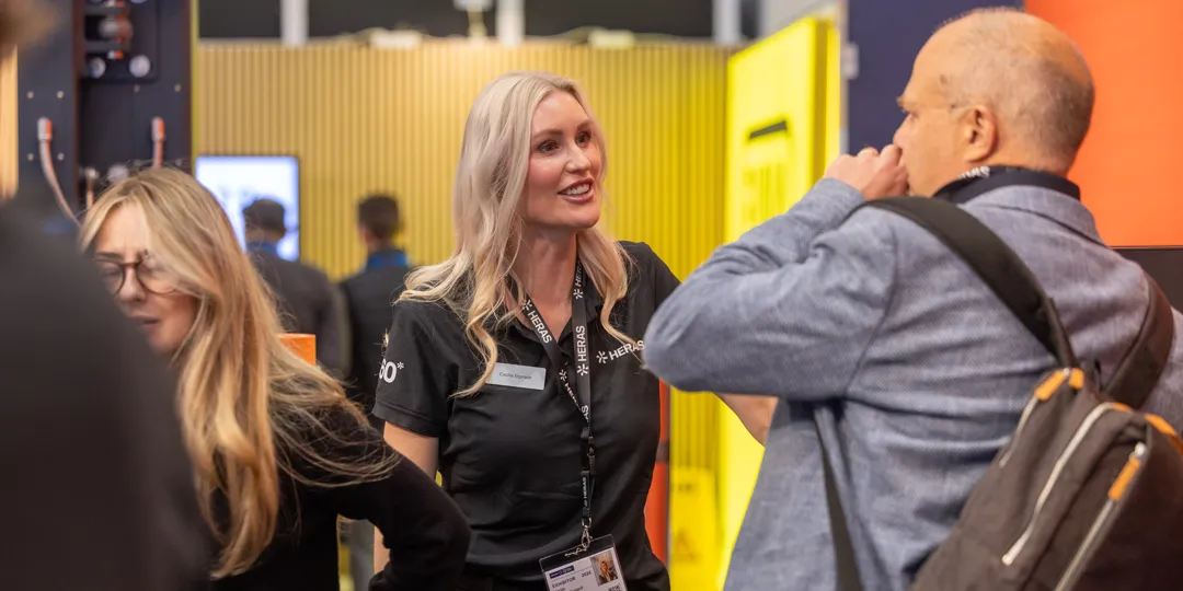 Skydd_Totalforsvar_LZ2_8226_Foto Liza Simonsson A representative from Heras speaks with a visitor in the exhibition hall during SKYDD 2026 at Stockholmsmässan.